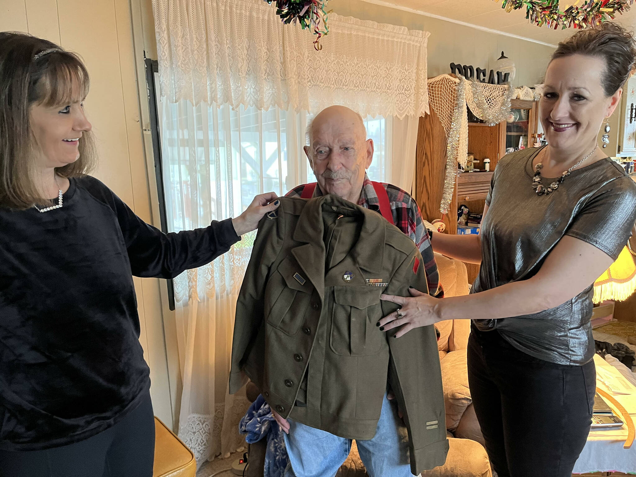 Matthew N. Wells | The Daily World 
Jodi Sund, left, and Jeri Bogar stand on both sides of their 97-year-old hero grandfather — U.S. Army Private First Class Harold Ralkey. Ralkey, who spoke about some of his experience on Friday, Nov. 26, 2021, at his mobile home in Elma, served in the 5th Infantry Division in World War II.