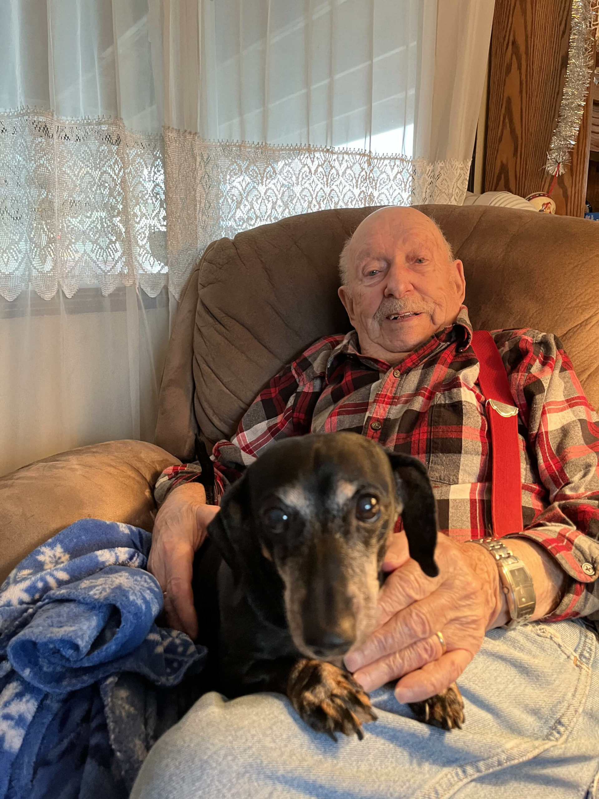 Matthew N. Wells | The Daily World 
Retired Pvt. First Class Harold Ralkey, 97, lounges with “Pretty Girl,” an 8-year-old dachshund, on Friday, Nov. 26, 2021, inside Ralkey’s home in Elma. Ralkey’s daughter, Carol Bogar, said the dog keeps him alive. “She sleeps with him under the covers,” she said. “That’s his baby.”