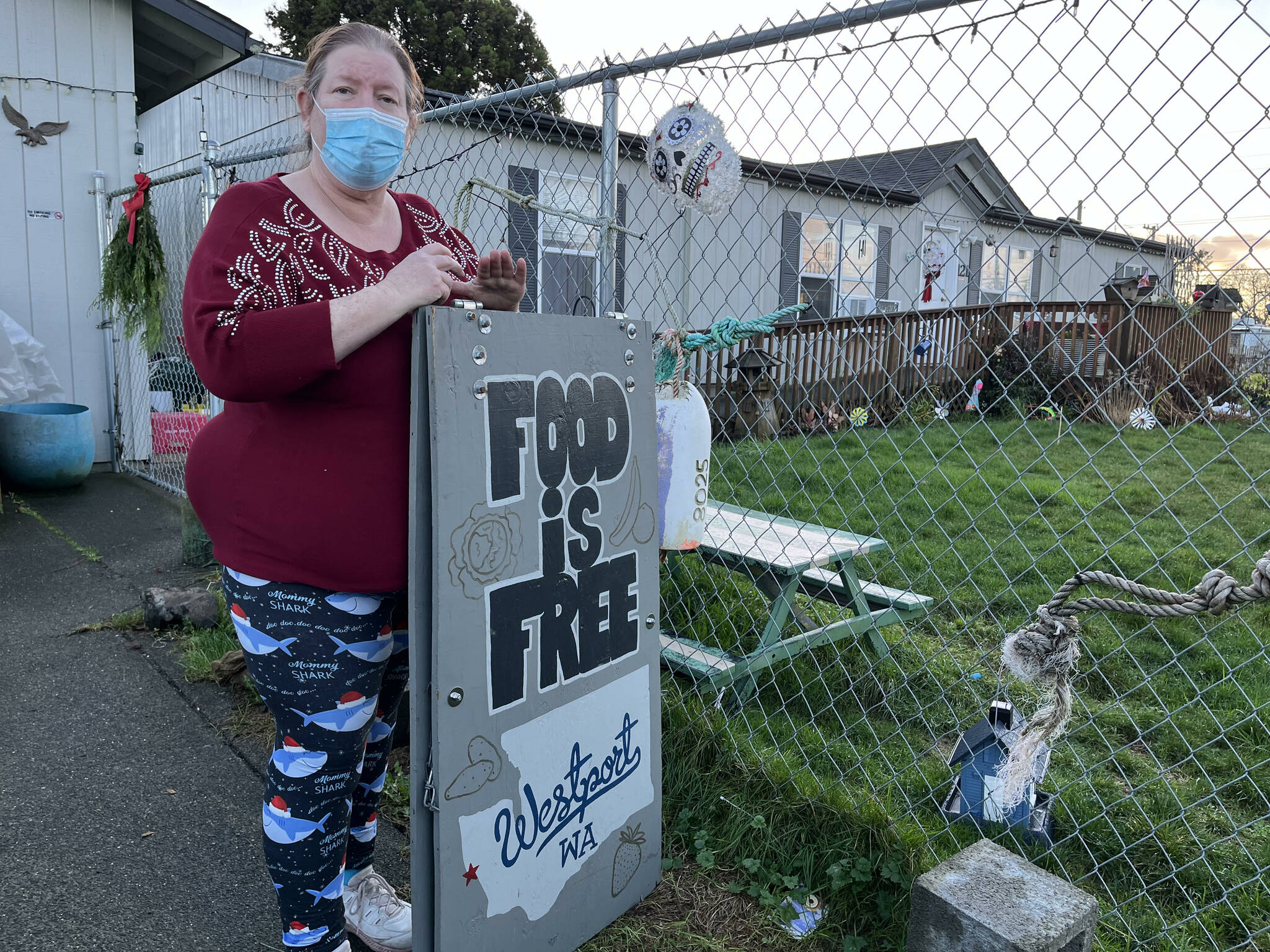 Matthew N. Wells | The Daily World 
Connie Airey, from Westport, holds up the sign that lets her neighbors know that if they’d like food to help them make ends meet, or to spend their money on something else they need, it’s available.