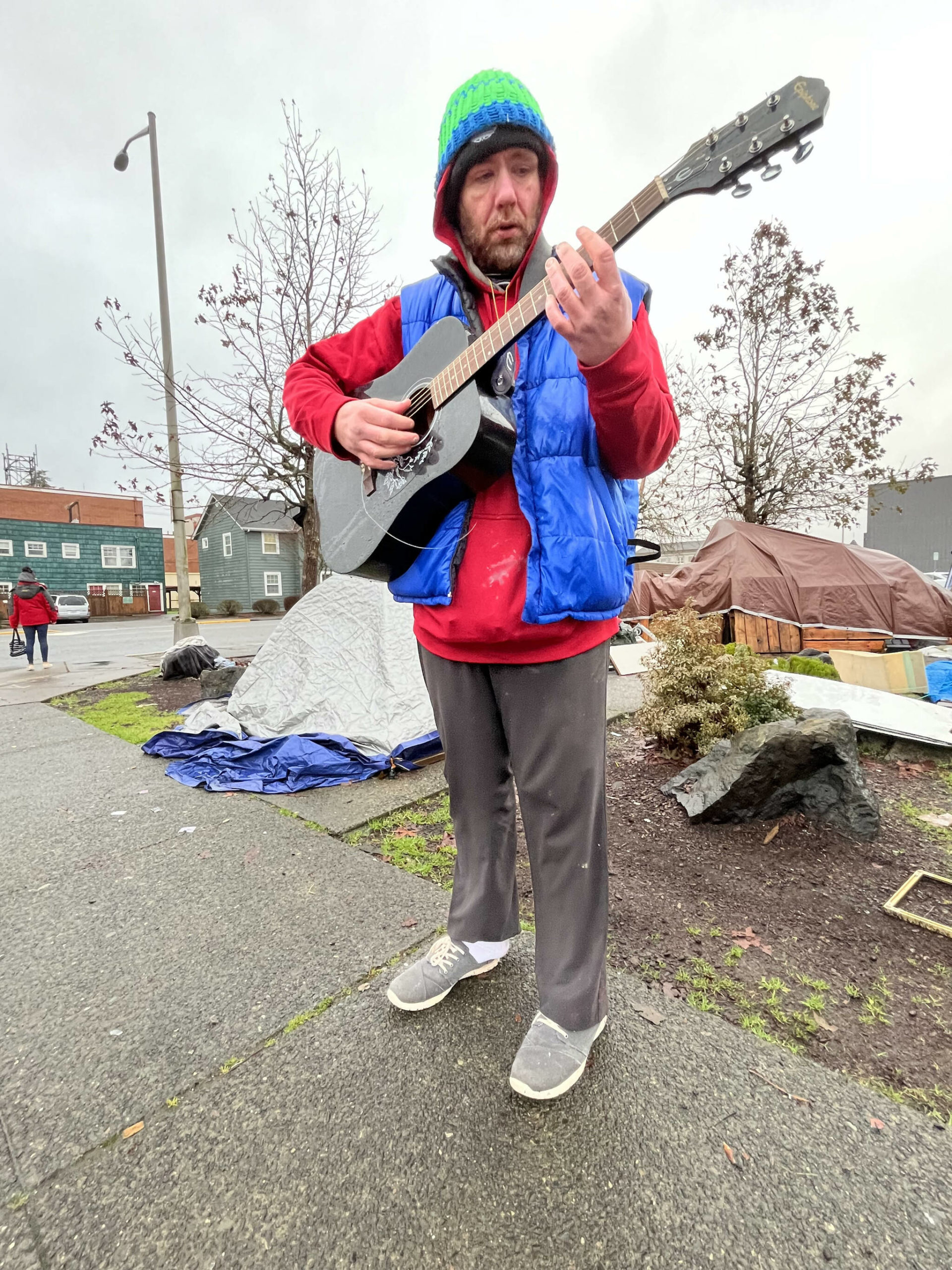 Matthew N. Wells | The Daily World 
Andrew “Drew” Carey plays his Epiphone acoustic guitar, with four working strings, on Friday Jan. 7, 2022, at the now non-sanctioned homeless encampment behind Aberdeen City Hall. The camp was closed after a narrow city council vote in November 2021.