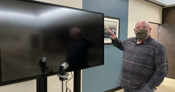 Aberdeen Mayor Pete Schave shows off the new 70-inch television screen that will help council members see members of the public who tune in, via Zoom, to council meetings when their meetings change from a remote setting to a hybrid setting. Currently, Schave said the plan is to switch from remote to hybrid at the Wednesday, March 9, 2022 meeting. (Matthew N. Wells | The Daily World)