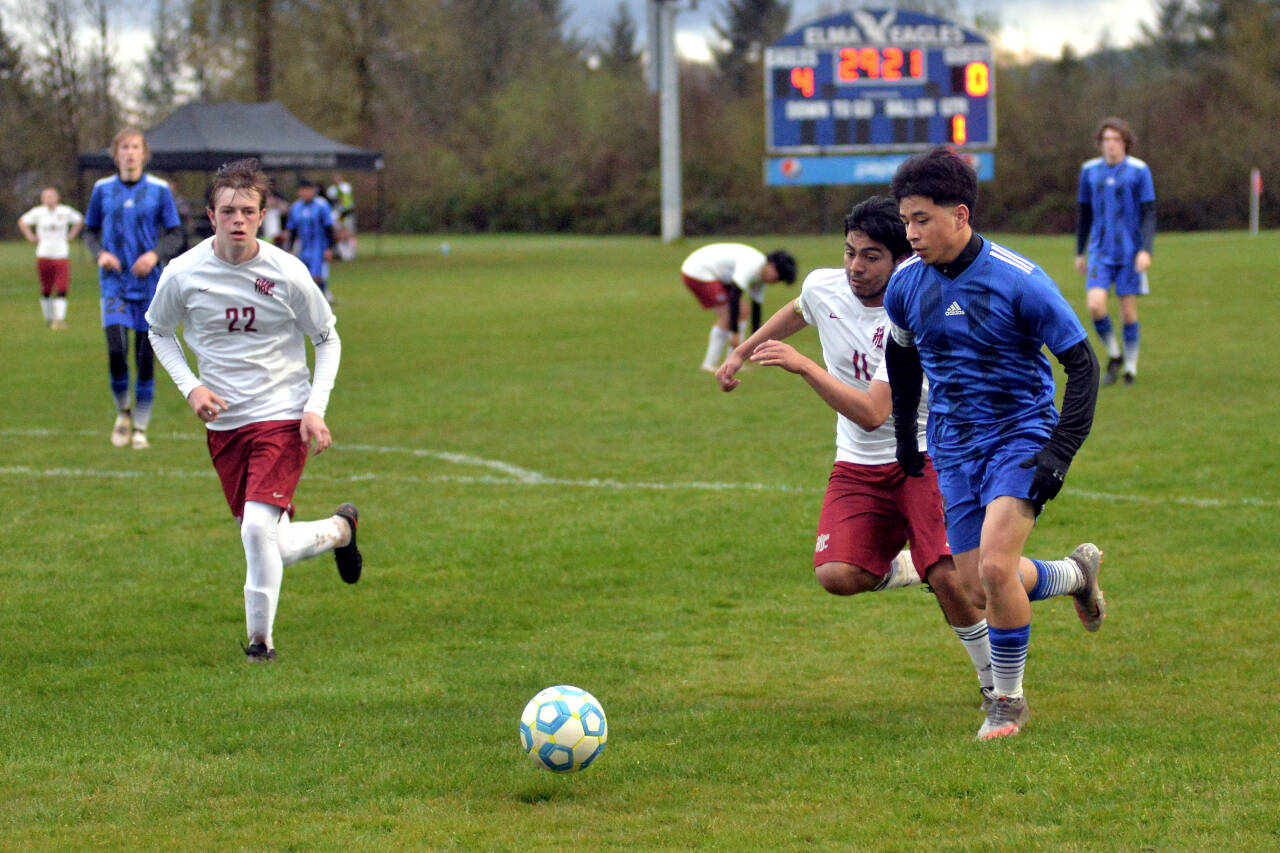RYAN SPARKS | THE DAILY WORLD Elma senior Manny Hernandez, right, is pursued by Hoquiam defenders Daniel Cortes Verdejo (11) and Mason Kelly (22) during Elma’s 9-0 win on Wednesday in Elma. Hernandez scored a goal and added two assists in the victory.