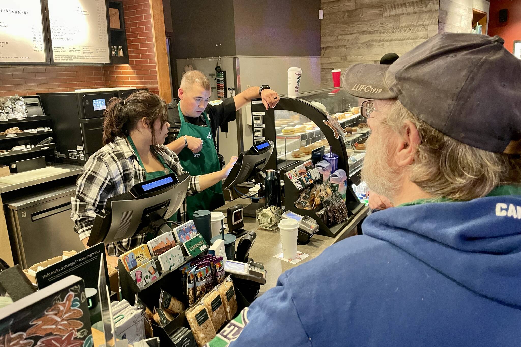 Michael S. Lockett / The Daily World 
Detective Stephen Heller, in green apron, reckons with the register during Badges & Brews, hosted at Starbucks.