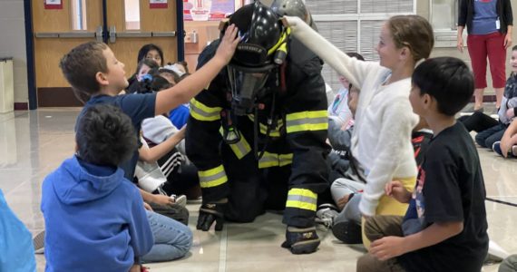 Michael S. Lockett | The Daily World
Firefighter/EMT James Freed crawls in full kit through a group of second graders at McDermoth Elementary School during a Fire Prevention Week presentation from the Aberdeen Fire Department on Monday.