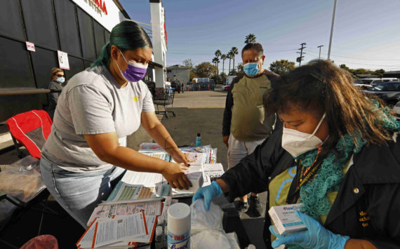 Soledad Enrichment Action community health workers Vivian Ramirez, left, and Maria Mejia, right, distribute COVID-related resources at a supermarket on Whittier Boulevard in Los Angeles last week. (Carolyn Cole/Los Angeles Times/TNS)