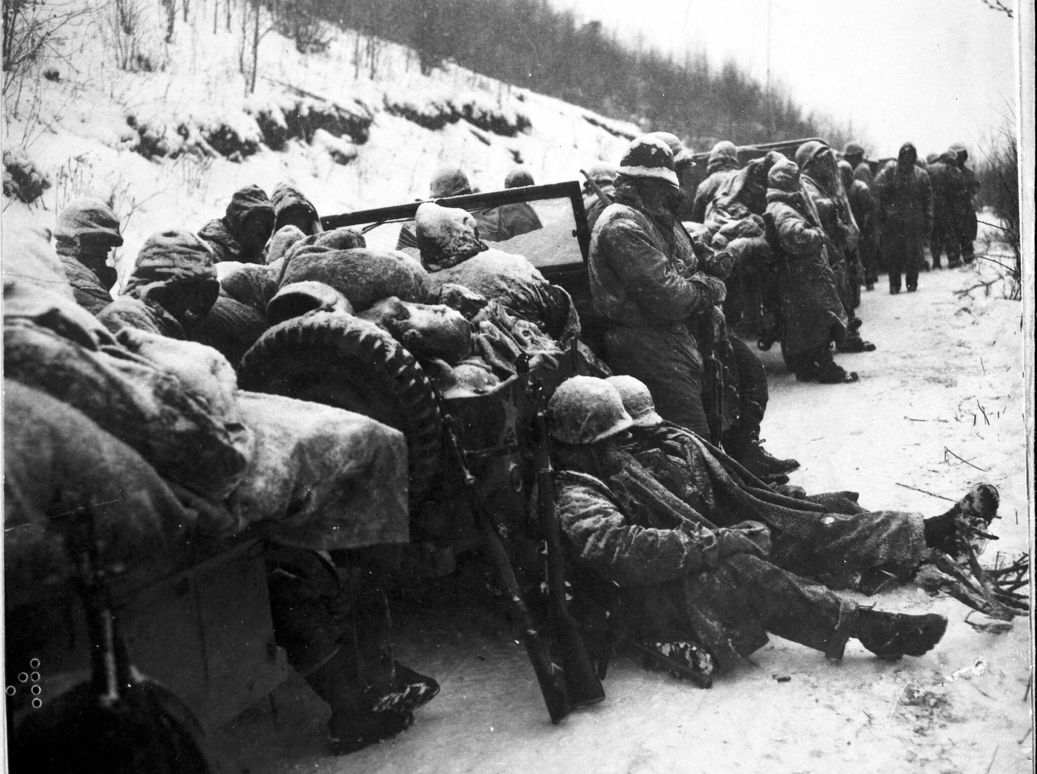 Marines of the 5th and 7th regiments who hurled back a surprise onslaught by three Chinese communist divisions wait to withdraw from the Chosin Reservoir area circa December 1950. (National Archives photo)