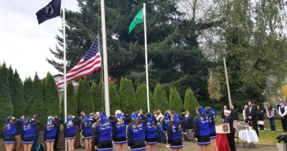 Members of the Elma High School Dance Drill team stand and salute as a new flag is hoisted to half-staff to celebrate Veterans Day during the memorial ceremony at the Elma Veterans Memorial Park.