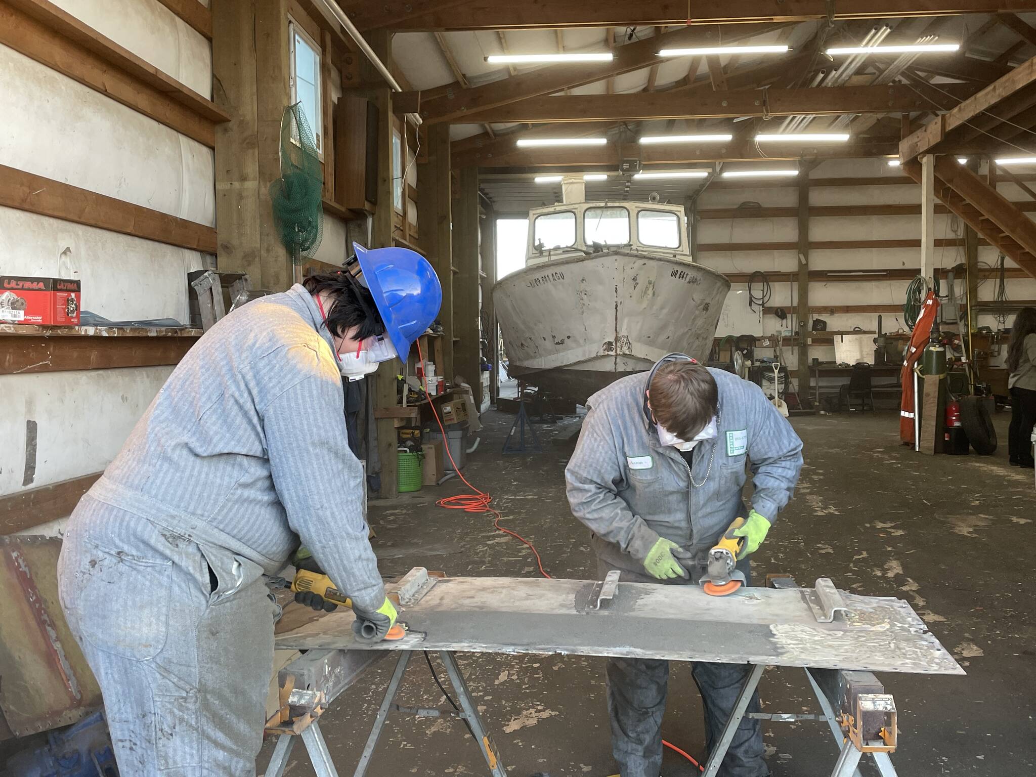 Evan Brockhoff and Logan Slosson, students with the Ocosta High School’s Maritime afterschool program, buff out a deckplate as part of a boat restoration on Nov. 9. (Michael S. Lockett / The Daily World)