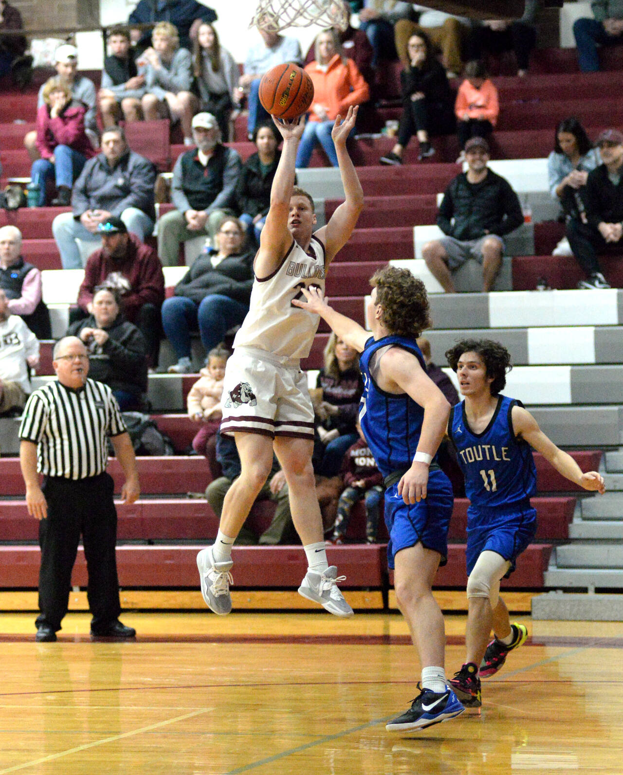 RYAN SPARKS | THE DAILY WORLD Montesano junior Tyce Peterson (23) hits a pull-up jumper while being defended by Toutle Lake’s Zach Swanson and Noah Younker (11) during the Bulldogs’ 64-38 loss on Saturday in Montesano.