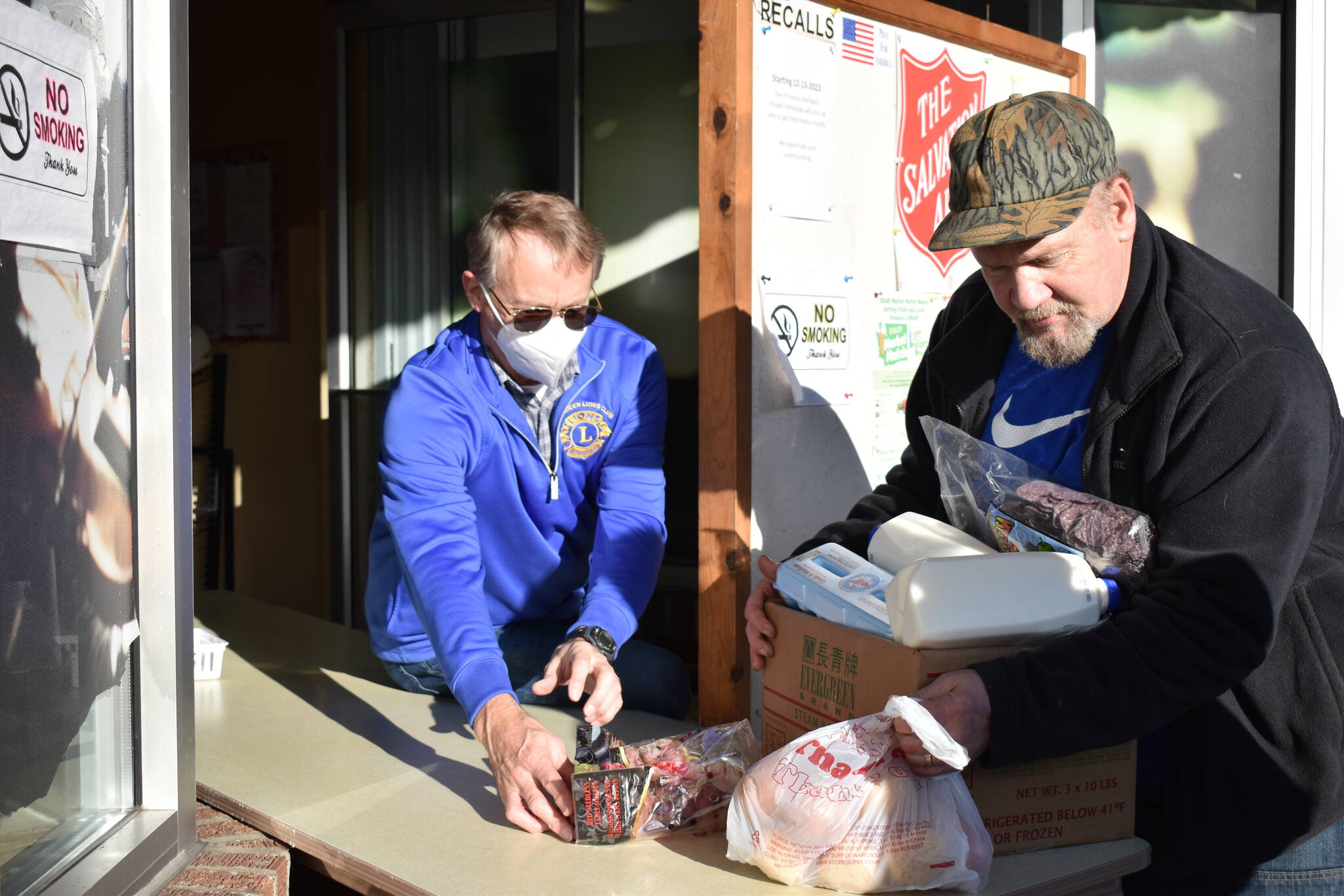 Volunteer Greg Johnstone, left, slides a box of food to Jerry Nelson Dec. 15 at the Aberdeen Salvation Army food pantry, 120 W Wishkah St. The pantry serves roughly triple the amount of people it did one year ago. (Clayton Franke / The Daily World)