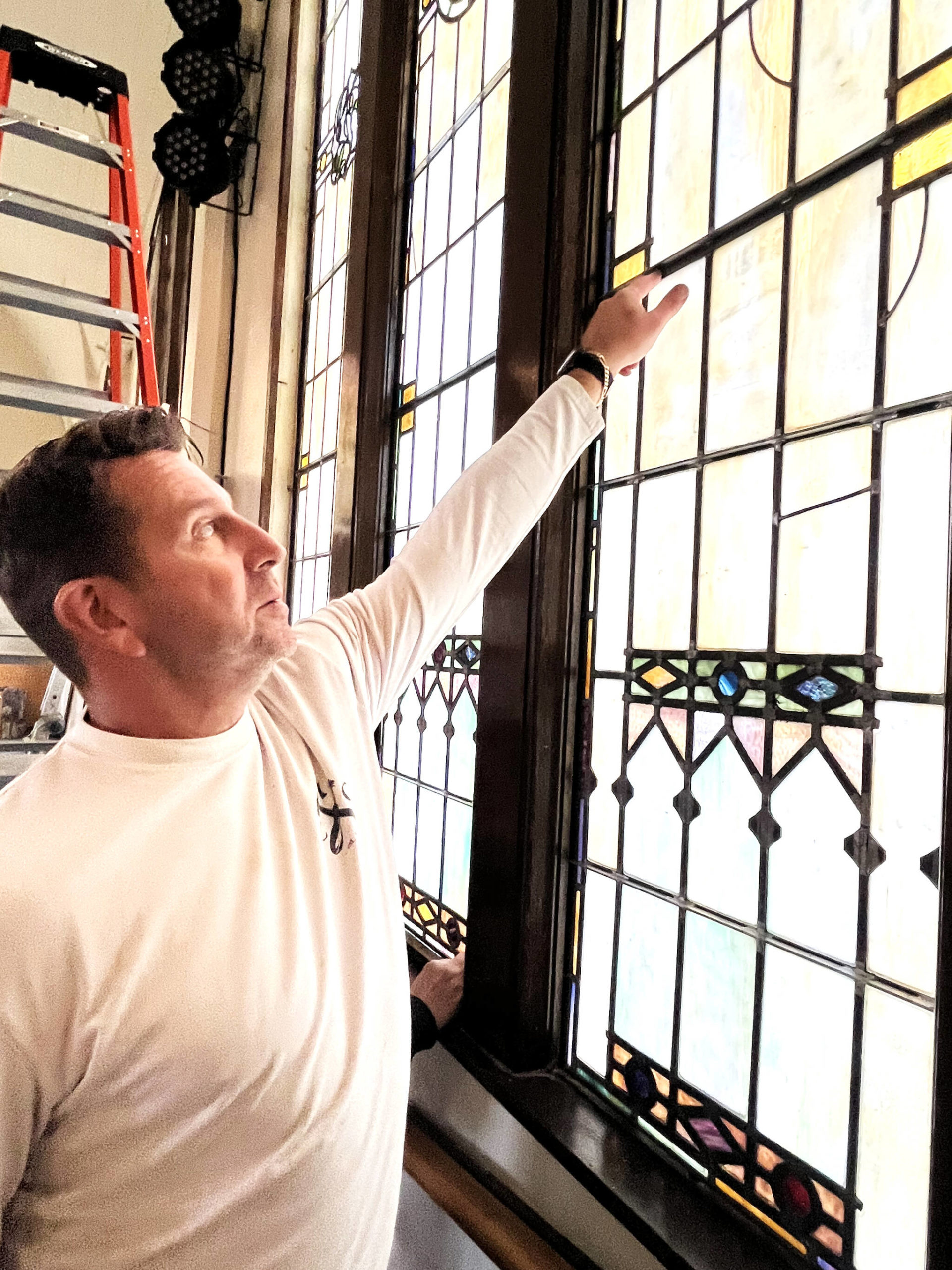 Matthew N. Wells / The Daily World 
Eric Penic, president of Cathedral Crafts Stained Glass Company, out of Winona, Minnesota, explains how the stained glass at Amazing Grace Lutheran Church of Grays Harbor wasn’t too hard to lift or place. He’s pointing to the support braces for the lancets that split the windows into different panels, which makes the windows easier to lift and place.