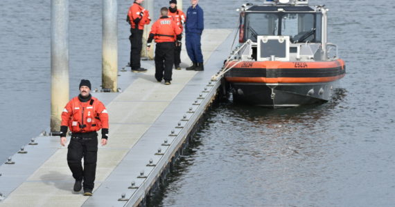 Courtesy photo / Ezra McCampbell 
Coast Guard personnel stand on a pier near Tokeland after assisting in the recovery of two fishermen who capsized while pulling up a crab pot on Monday, Jan. 16.