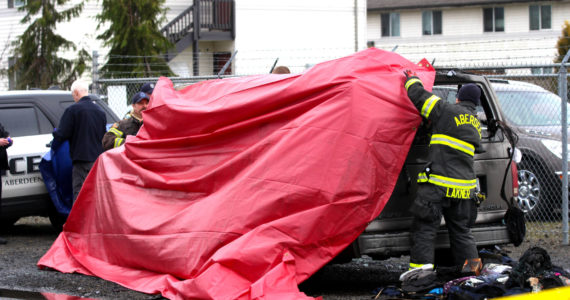 Firefighters stretch a tarp over the aftermath of a vehicle fire that killed a man in South Aberdeen on Tuesday, Jan. 24. (Michael S. Lockett / The Daily World)