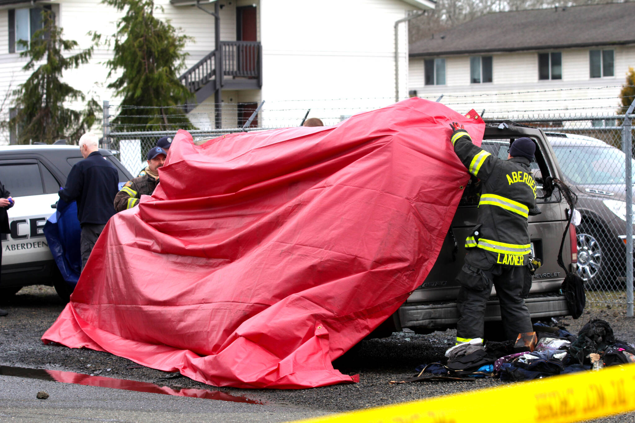 Firefighters stretch a tarp over the aftermath of a vehicle fire that killed a man in South Aberdeen on Tuesday, Jan. 24. (Michael S. Lockett / The Daily World)