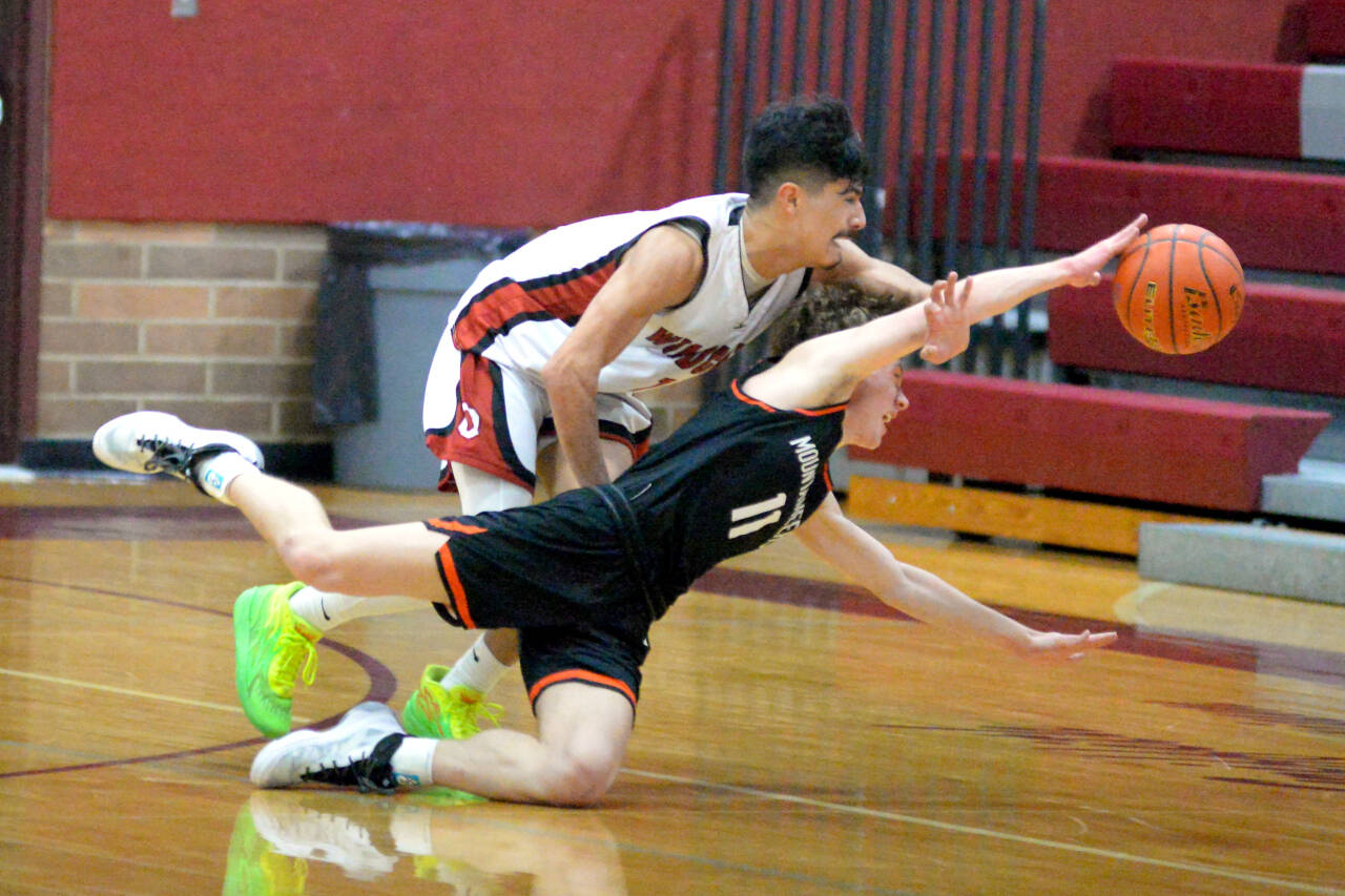 RYAN SPARKS | THE DAILY WORLD Ocosta’s Josh Figueroa, top, chases a loose ball against Rainier’s Jimmy Meldrum during the Wildcats’ 64-62 loss in the first round of the 2B District 4 Tournament on Saturday at Montesano High School.