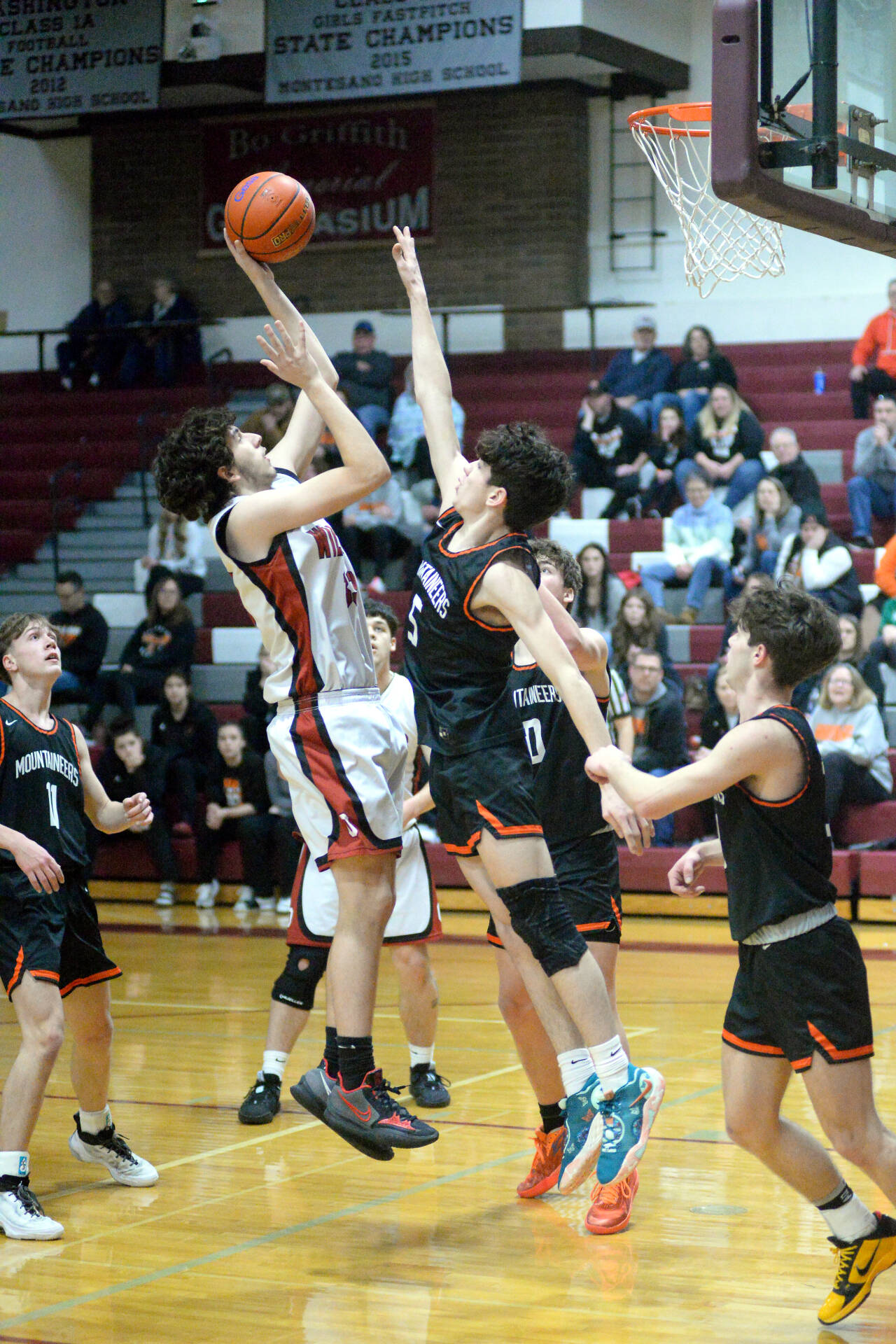 RYAN SPARKS | THE DAILY WORLD Ocosta’s Mark Lewis, left, scores against Rainier’s Gavin Owen (5) during the Wildcats’ 64-62 loss in the first round of the 2B District 4 Tournament on Saturday at Montesano High School.