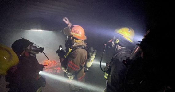Chief Dennis Benn of the South Beach Regional Fire Authority, hand raised, demonstrates thermal layering from fire in an enclosed space during a firefighter academy in Westport on Feb. 18. (Michael S. Lockett / The Daily World)