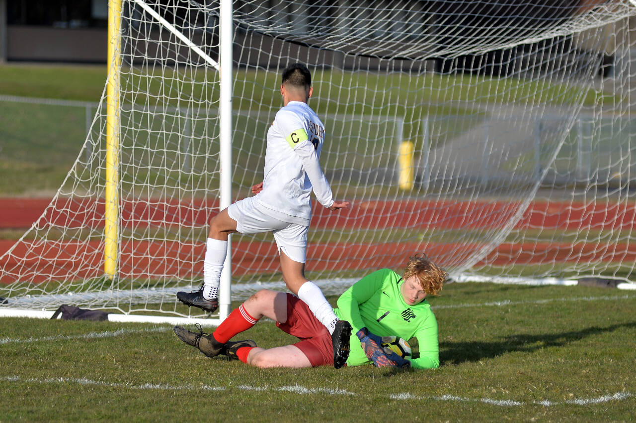 Hoquiam goal keeper Nick Estes slides to make a save against an oncoming Edwin Quintana during the Bobcats’ 10-0 win on Wednesday at Sea Breeze Oval in Hoquiam.