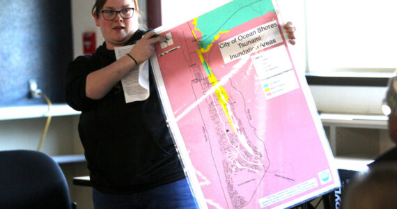 Ocean Shores Elementary School teacher Haley Stoney holds the inundation map of Ocean Shores during a school board meeting on March 21. The construction of a tsunami tower for the low-lying school has proved contentious with the public. (Michael S. Lockett / The Daily World)