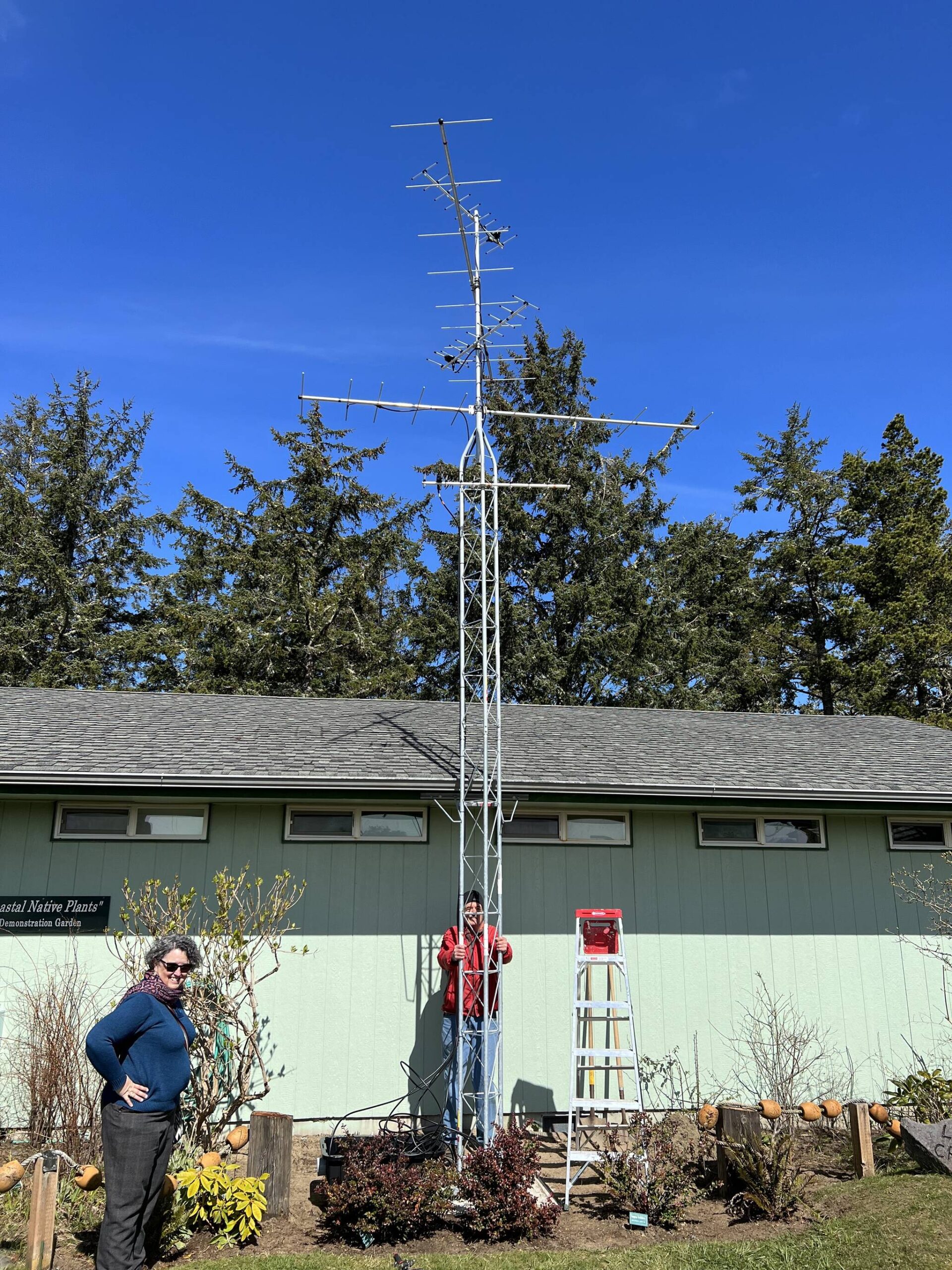 Barbara Hayford, left, executive director of the Coastal Interpretive Center, and volunteer Bob Krueger stand with the new Motus tower on Monday, March 27 at the interpretive center in Ocean Shores. (Clayton Franke / The Daily World)