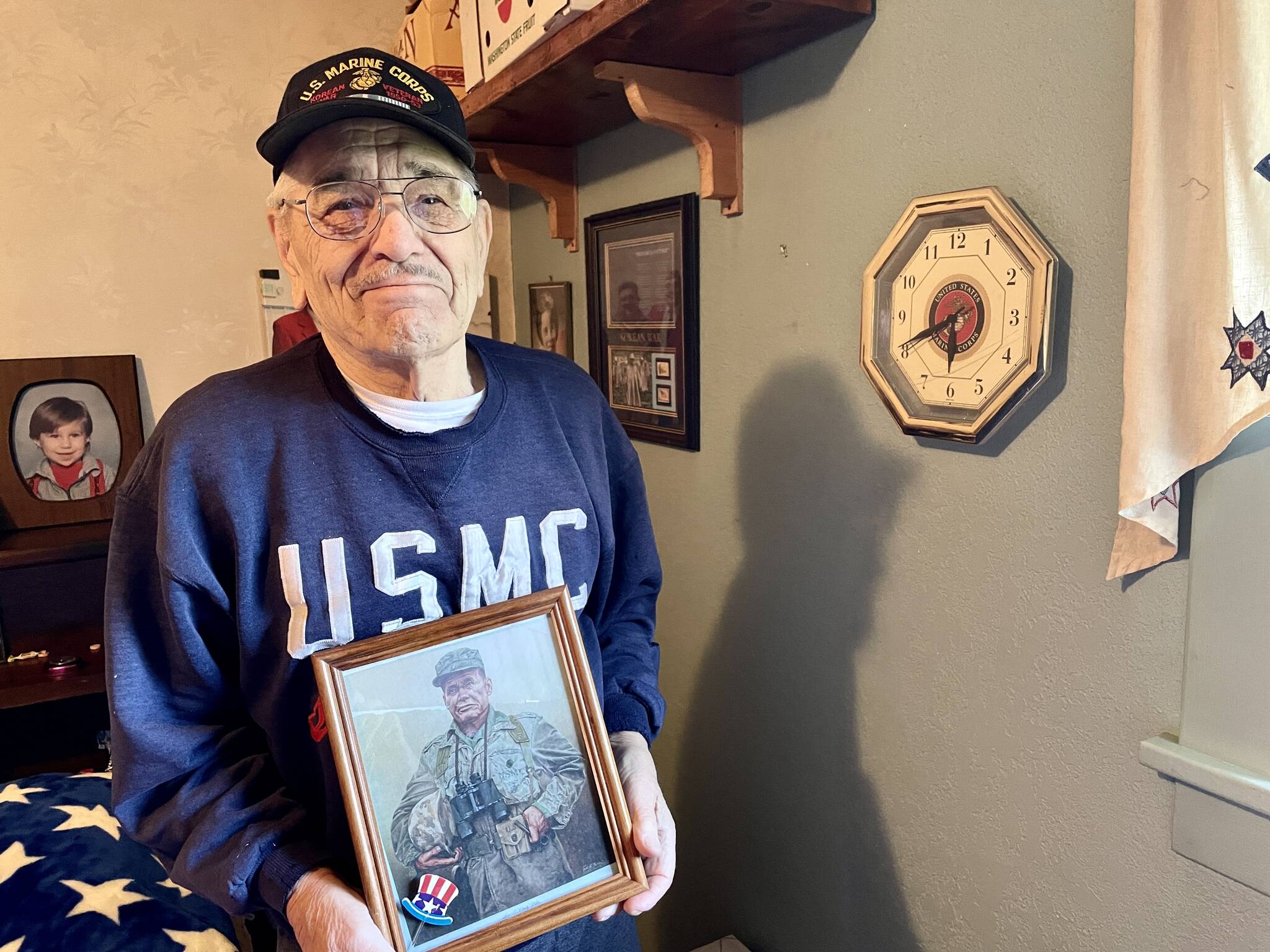 Jim Evans, one of the Chosin Few, poses in his residence with a picture of Marine Corps legend “Chesty” Puller. (Michael S. Lockett / The Daily World)