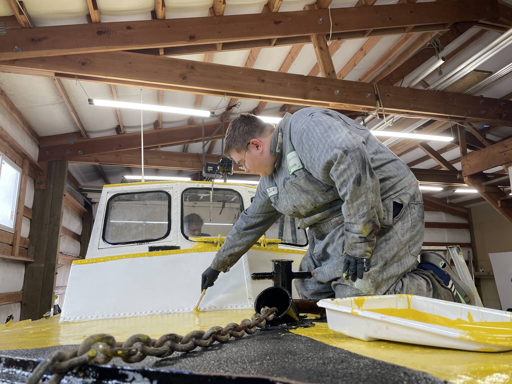 Evan Brockhoff, a student in Ocosta High School’s maritime program, paints an old Coast Guard lifeboaty. (Michael S. Lockett / The Daily World)
