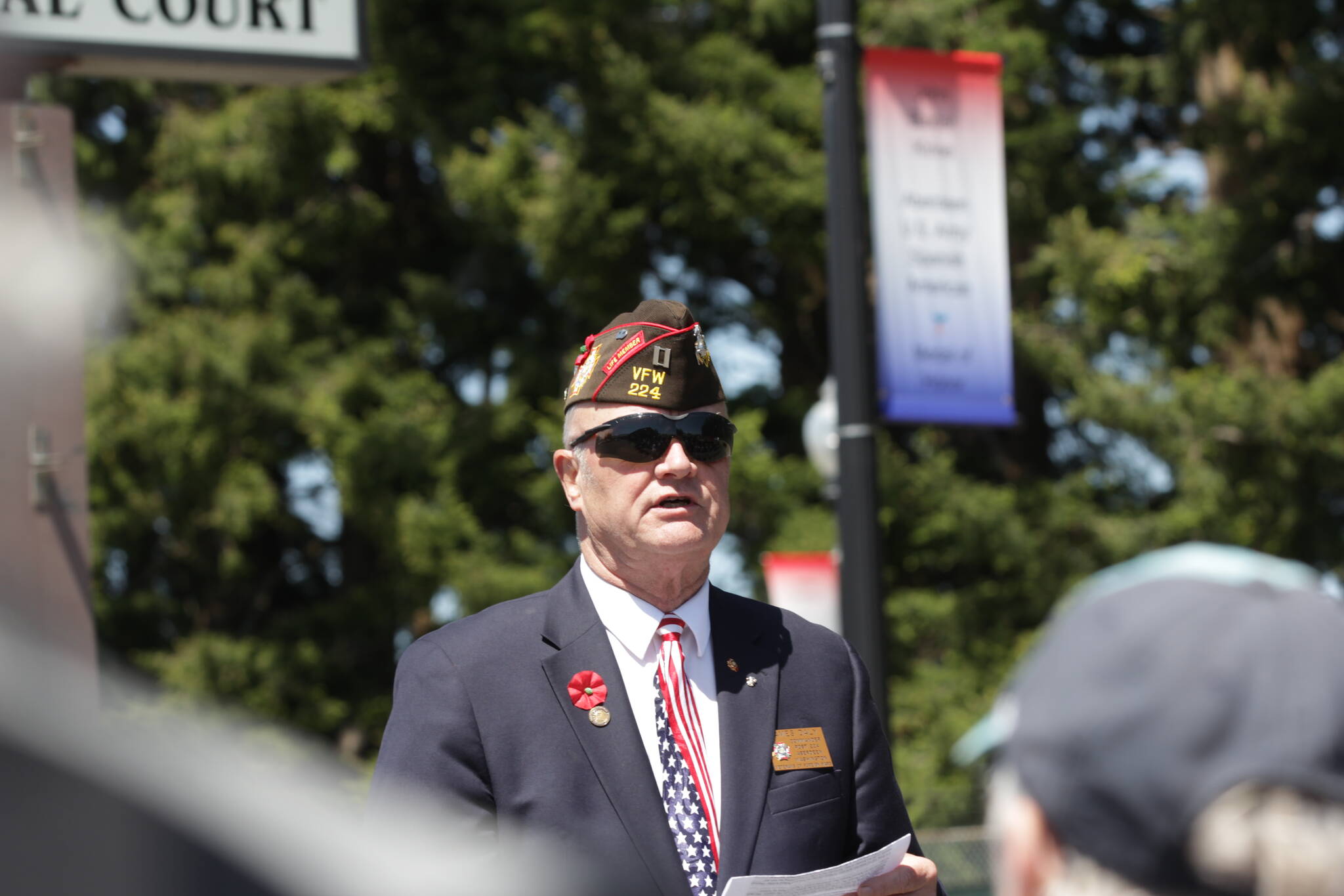 Veterans of Foreign Wars Post 224 Chaplain Jim Daly speaks during the dedication ceremony for banners honoring the war dead of the county in Cosmopolis, one visible behind Daly, on Memorial Day, May 29. (Michael S. Lockett / The Daily World)