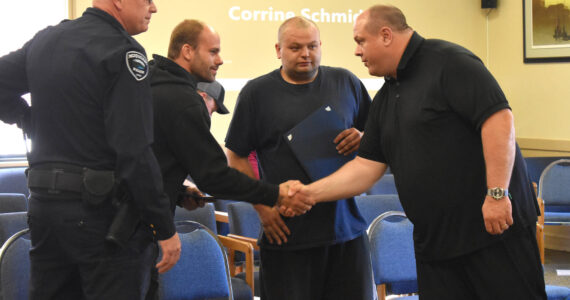 Matthew N. Wells / The Daily World
Hoquiam Police Chief Joe Strong, from left, stands as Jeffery L. Alderton II shakes Hoquiam Mayor Ben Winkelman’s hand. Robert Olson, who along with Alderton played a “critical” part in stopping a kidnapping on May 15, holds his commendation.