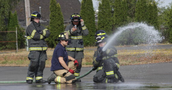 Michael S. Lockett / The Daily World
Derek Jensen of the Hoquiam Fire Department, in blue T-shirt, teaches a group of high schoolers taking part in a fire science program about using a firehose on July 13.