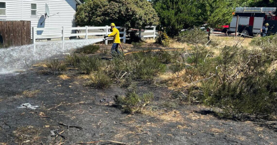 Michael S. Lockett / The Daily World
Firefighter/EMT Nick Frymire of the Ocean Shores Fire Department sprays down a burned area caused by a grass fire on July 18.