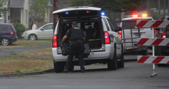 A sheriff’s deputy pulls an equipment case out of a vehicle during a standoff in Hoquiam on Aug. 28. (Michael S. Lockett / The Daily World)
