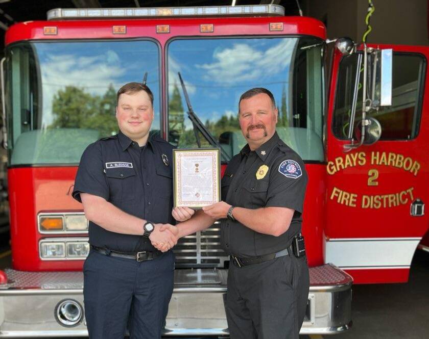 Chief John McNutt, right, of Grays Harbor Fire District 2, presents volunteer firefighter Aaron Bledsoe with the Life Saving Medal for his actions earlier in the year saving the life of a neighbor in a fire. (Courtesy photo / GHFD2)