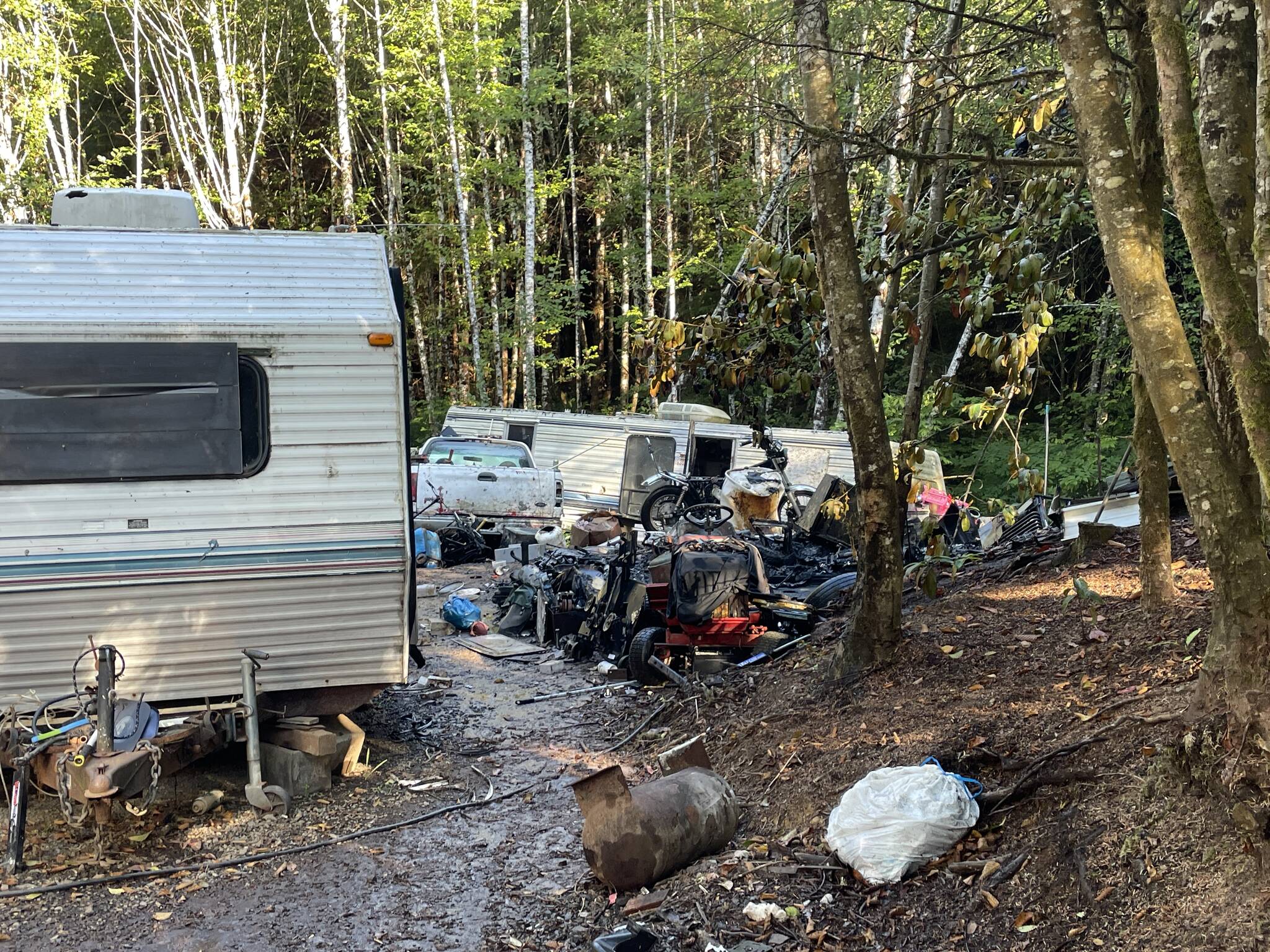 A fire on Thursday morning completely destroyed a trailer, visible on the right, in a camp off State Route 105. (Michael S. Lockett / The Daily World)