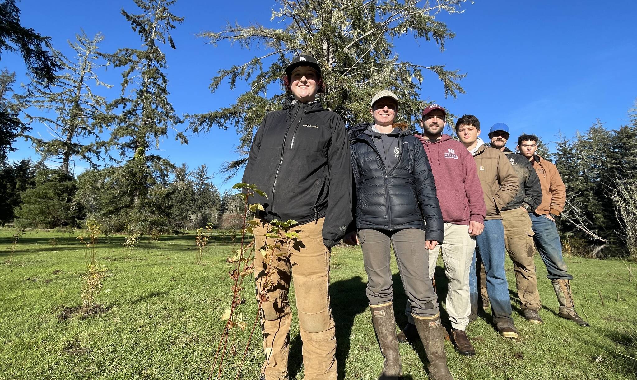 Grays Harbor Conservation District’s work crew poses behind a tree they recently planted, one of thousands, as part of a riverbank repair effort. (Michael S. Lockett / The Daily World)