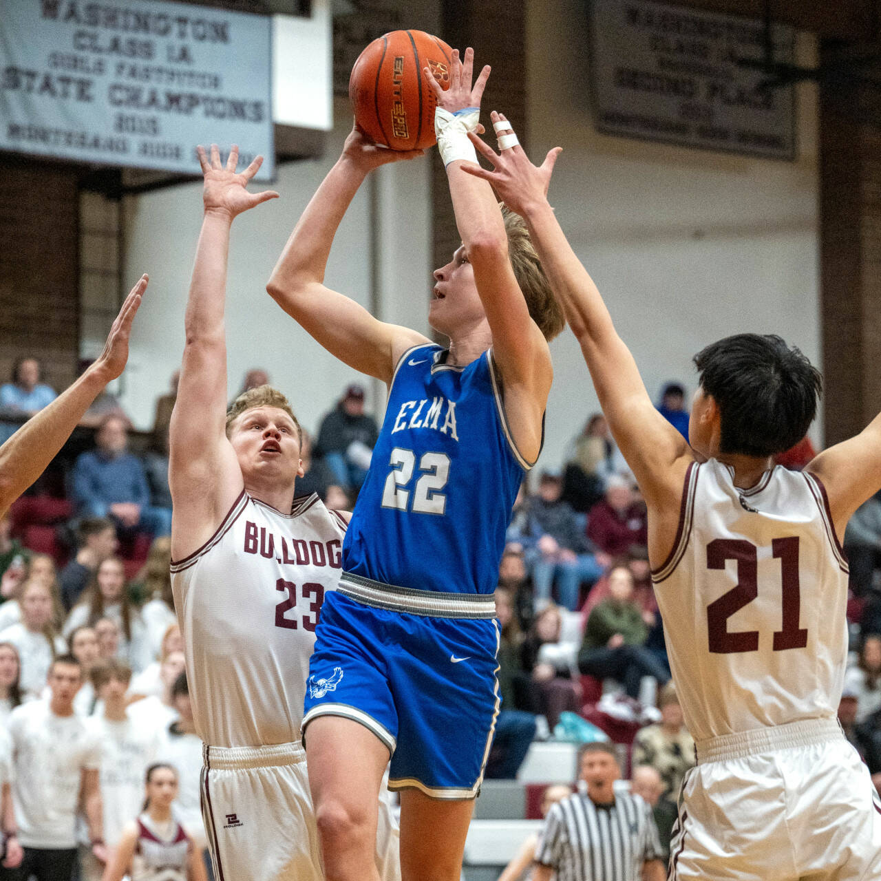 PHOTO BY FOREST WORGUM Elma’s Cason Seaberg (22) drives to the basket against Montesano’s Tyce Peterson (23) and Delon Chan during the Eagles’ 56-53 win on Tuesday in Montesano.