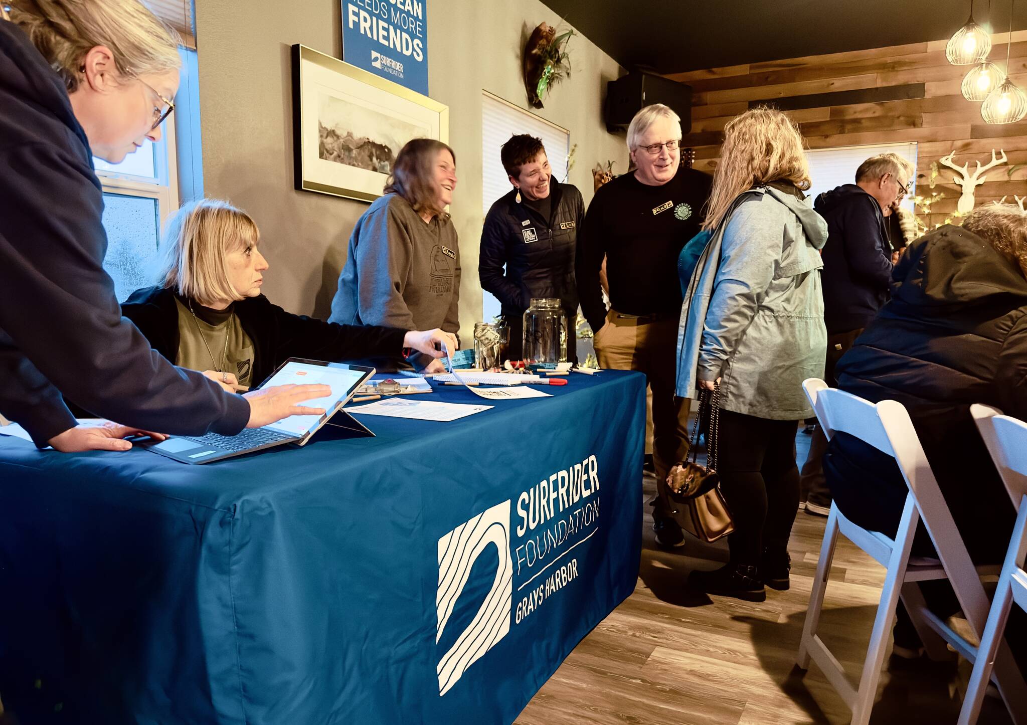 Kimberly Johnson / Surfrider Grays Harbor
Local chapter chair Bruce Rittenhouse and state coordinator Liz Schotman, center, converse with an attendee at a launch party for the Surfrider Foundation’s new Grays Harbor chapter at the Oyhut Bay Grill in Ocean Shores on Feb. 27.