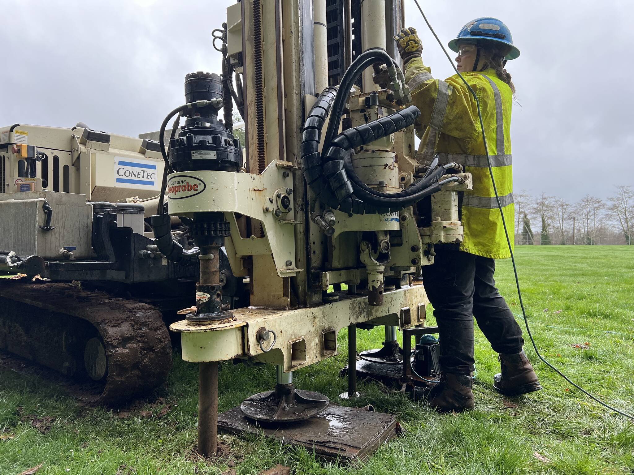 Emily Bayes, an assistant field geologist with ConeTec, the company hired to conduct soil stability assessments at the Hoquiam School District, operates a drilling machine at the Hoquiam High School baseball field on Feb. 21. (Clayton Franke / The Daily World)