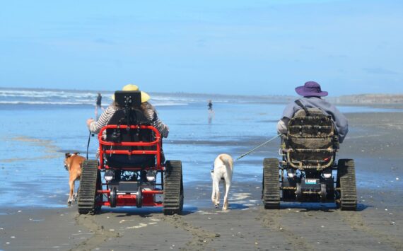 Courtesy photo / John Shaw
A pair of guests make their way down Westport beach using tracked mobility chairs from David’s Chair, a nonprofit partnering with the city to help bring the beach to more people.