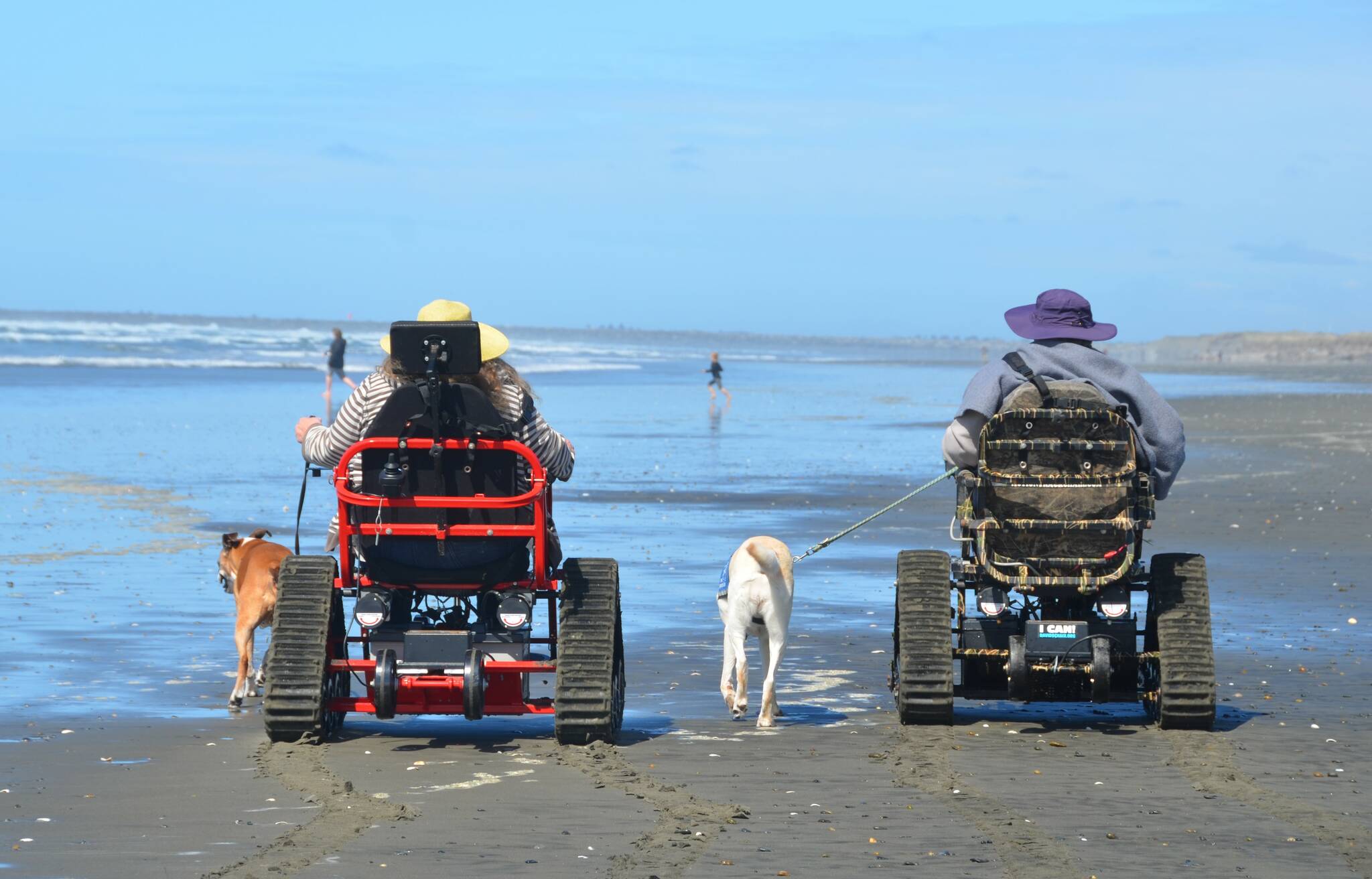 A pair of guests make their way down Westport beach using tracked mobility chairs from David’s Chair, a nonprofit partnering with the city to help bring the beach to more people. (Courtesy photo / John Shaw)