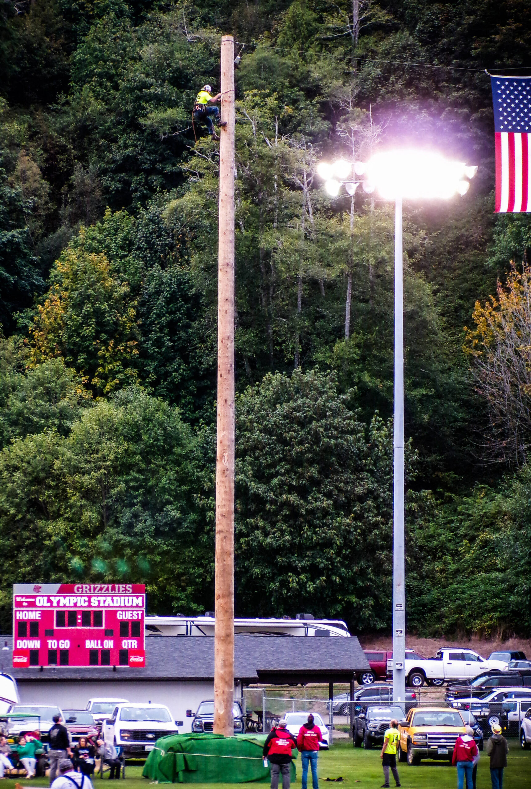 A logger scrambles to the top of a tall pole.