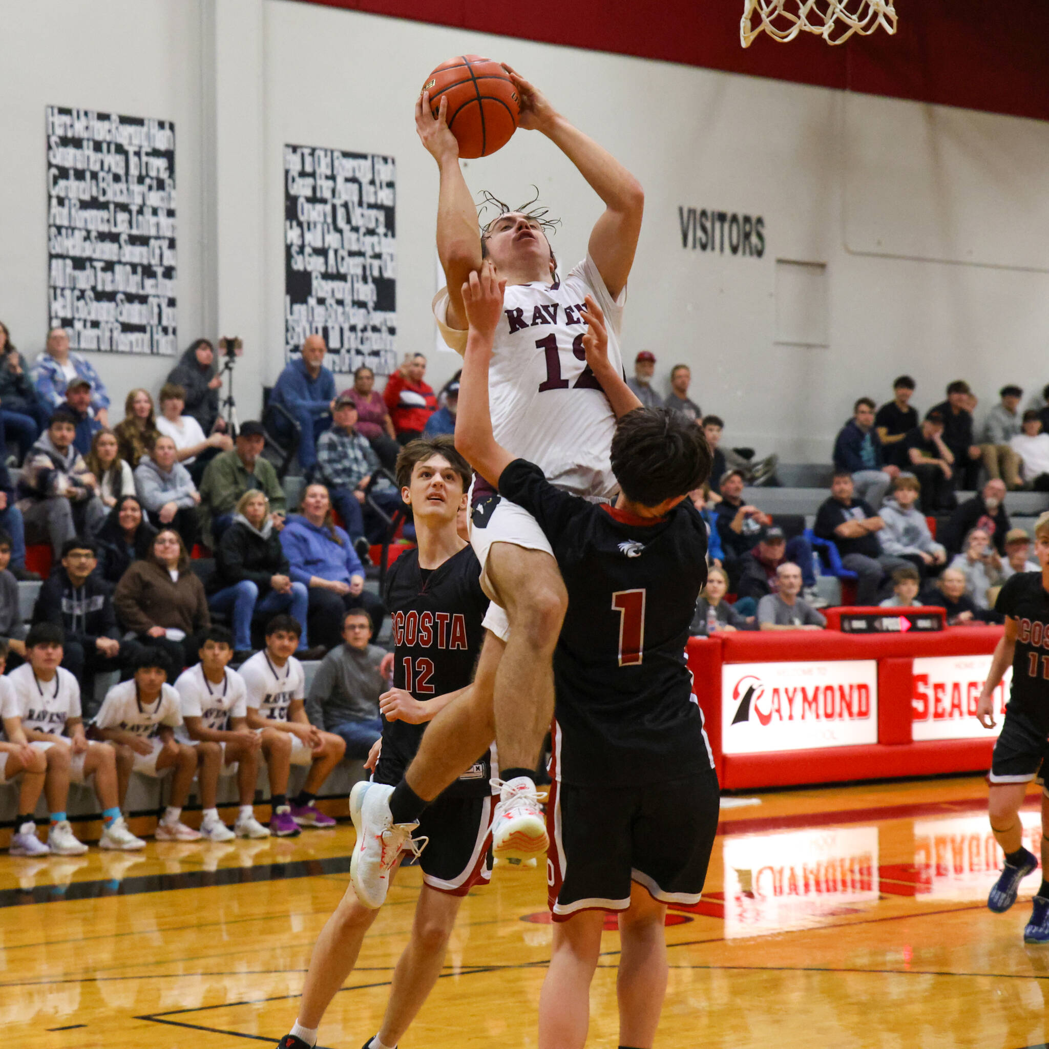 PHOTO BY LARRY BALE Raymond-South Bends Chris Banker (12) goes up for a shot while defended by Ocostas Bryce Bottleson (1) and Brayden Dungey during a game on Wednesday at Raymond High School. Ocosta won in overtime 73-68.