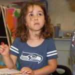 (Stephanie Morton | The Vidette)                                Makenzie Hart uses her fingertip to paint red apples on a tree as part of an assignment in Ms. Cady&rsquo;s kindergarten class on Friday.