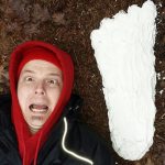 Johnny Manson poses next to a casting of a Sasquatch footprint.