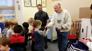 Joe Cornell of the nonprofit organization &ldquo;Making a Difference for Grays Harbor Kids&rdquo; hands a pair of gloves to a student Thursday at McDermoth Elementary School in Aberdeen as Principal Brandon Winkelman looks on. (Terri Harber|The Daily World)