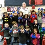 Joe Cornell poses with second graders at McDermoth Elementary School on Wednesday. The kids are modeling gloves Cornell distributed to them and the other nearly 400 children there. (Terri Harber|The Daily World)