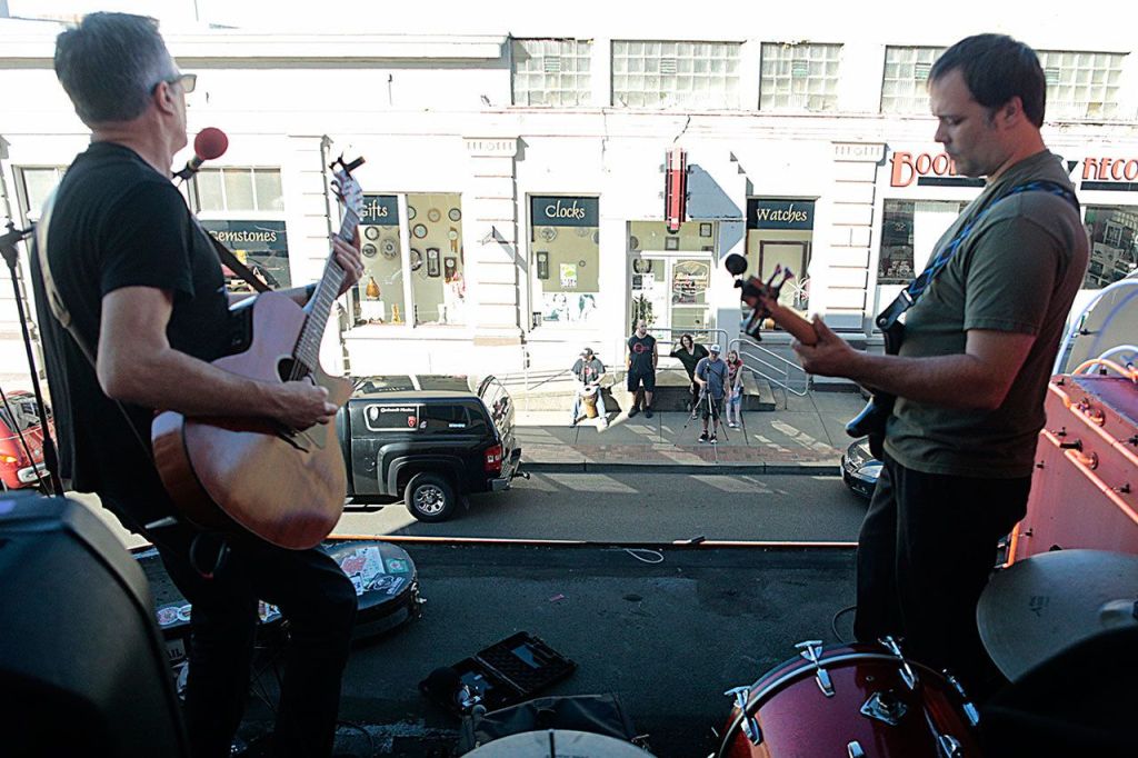 First Fridays are a staple of the burgeoning Aberdeen music scene, known as The Alley. That&rsquo;s when a dozen or more local businesses, ranging from bars to jewelry stores, invite local artists to share their music. The relationship is a symbiotic one, giving artists a chance to showcase their music and giving people a reason to travel to downtown Aberdeen to enjoy it. The driving force behind The Alley, Wil Russoul, kicks off a recent First Friday with an impromptu set atop the marquee at the D&R Theatre. With him is Michael B. Johnson, who studied music and Grays Harbor College and is continuing his music education at The Evergreen State College. Not pictured is drummer Evan Mehlhoff, who plays with the Aberdeen based band Vinyl Moon. In the background are Boomtown Records and Wiitamaki&rsquo;s Jewelers, both businesses who provide local musicians with places to play.