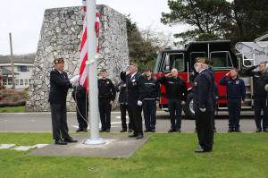 Angelo Bruscas | GFH Newspaper Group                                VFW Post 8956 members Dennis Hogan, Dan Martin, John Link and Jim Docherty present the flag with Ocean Shores firefighters in the background.