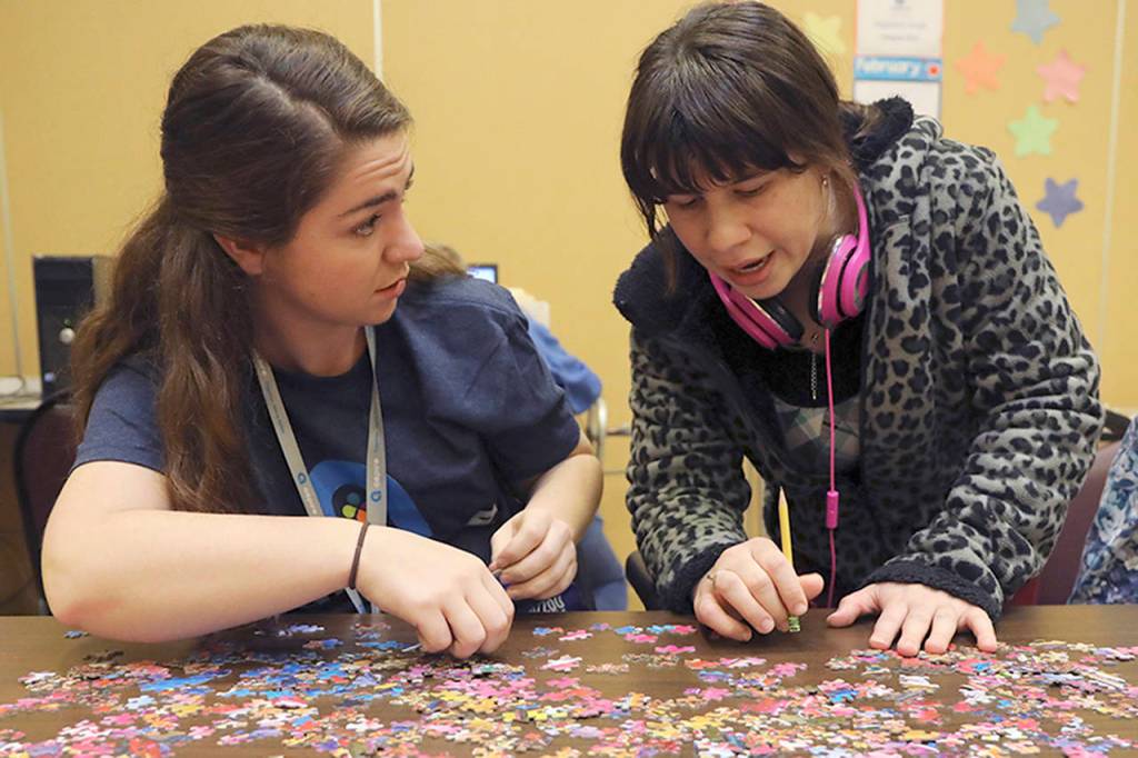 University of Missouri student Lillie Heigl, left, helps build a puzzle with clients with developmental disabilities during a free time session at the Aspire Career Academy.
