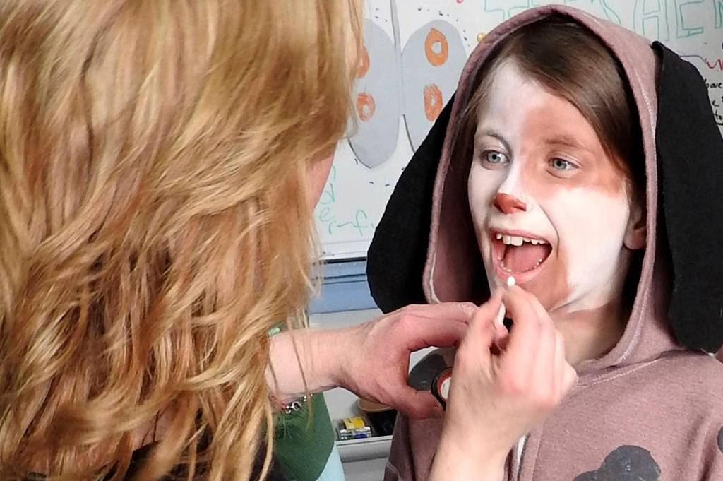 Gina Holmes, North River&rsquo;s paraprofessional for pre-K through first grade, puts the finishing touches on Kailey Greiner, who played Annie&rsquo;s dog, Sandy. Holmes supported the play in numerous ways, including &ldquo;getting the kids to their places on time and keeping the wild ones quiet backstage,&rdquo; according to Heather Johnson. She&rsquo;s also the mom of Kate Holmes, the high-school student who served as choreographer for &ldquo;Annie.&rdquo; (Photo by Kat Bryant | The Daily World)