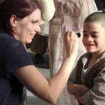Bridget Greiner, mom of Kailey (Sandy) and Destinee (Grace Farrell), applies blush to Micah Devine-Carter, a kindergartner who played an orphan. She also helped with the spaghetti dinner beforehand. (Photo by Kat Bryant | The Daily World)